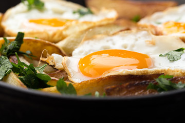 Breakfast in the pan. Fried potatoes with eggs in a skillet. Food bachelor. Cooked by a man. Hot and fresh. Homemade breakfast on black table. Fried eggs and sweet potato hash in cast iron skillet Fre