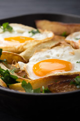 Breakfast in the pan. Fried potatoes with eggs in a skillet. Food bachelor. Cooked by a man. Hot and fresh. Homemade breakfast on black table. Fried eggs and sweet potato hash in cast iron skillet Fre