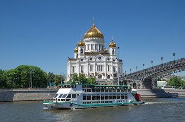 Fototapeta na wymiar A pleasure boat sails past the Church of Christ the Saviour. Moscow, Russia
