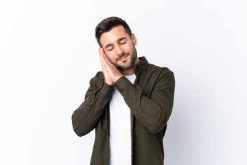 Young handsome man with beard over isolated white background making sleep gesture in dorable expression