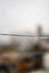 Clothesline wire full of small drops on a rainy day with a selective focus in the center very shallow depth of field