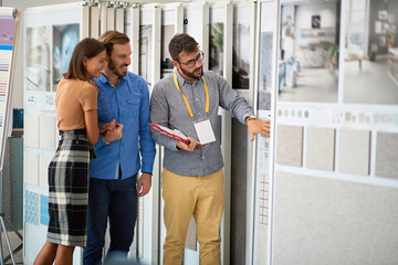 young couple talking with salesman abut interior decor at ceramic tiles store