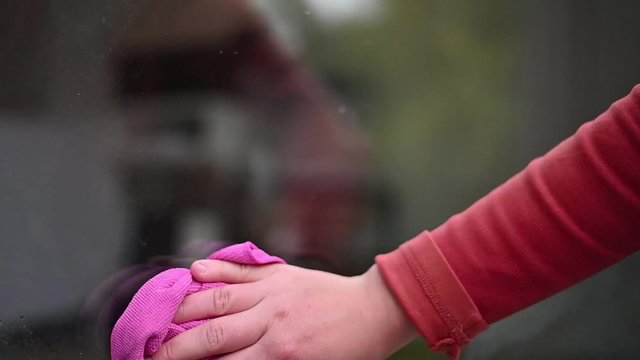 House cleaning. Girl clA beautiful woman struggling with house cleaning cleans the glass with a spray and a cloth on purpose. 