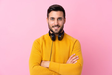 Young handsome man with earphones over isolated pink background smiling a lot