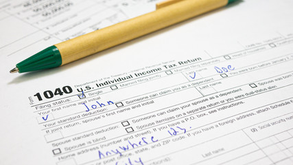 American 1040 Individual Income return tax form with green pen. Business financial concept. Fill multiple-use male name John Doe