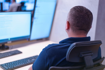 Security guard monitoring modern CCTV cameras in surveillance room.  Male security guard in surveillance room.