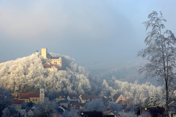 Winterzauber. Kleines Dorf mit Kirche am Fuß einer mittelalterlichen Burg im Raureif