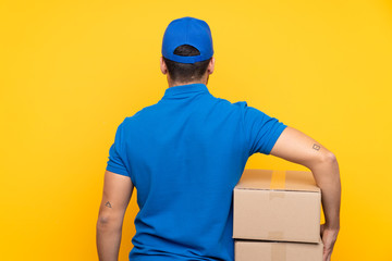 Delivery man over isolated yellow background in back position