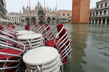 red chairs of alfresco cafe with water in saint Mark square in V