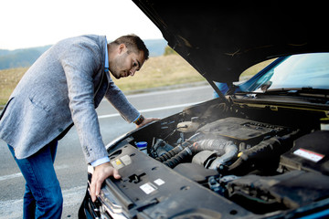 Desperate young man looking for a solution to a broken car