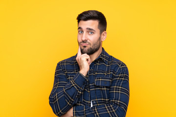Fototapeta premium Young handsome man with beard over isolated yellow background Looking front
