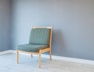Stylish soft wooden chair in an empty room. On a gray background.