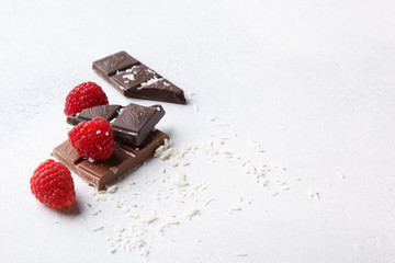 Dark and milk chocolate with raspberries, coconut shavings on a light background. Background image, copy space