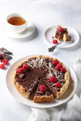 Chocolate cake with cottage cheese and raspberries with a cup of tea on a light background. Background image, copy space
