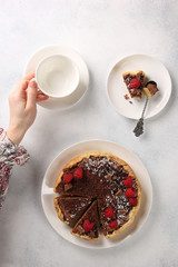 Chocolate cake with cottage cheese and raspberries  wiht hands on a light background. Background image, copy space