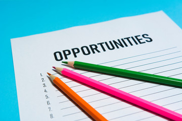 Opportunity text on white paper with list lines and pencils in various colors, concept.