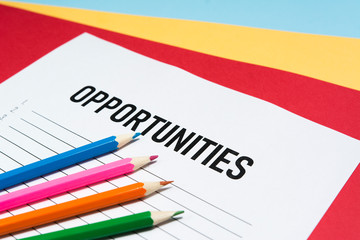 Opportunity text on white paper with list lines and pencils in various colors, concept.