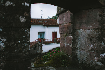 Old stone house in a french mountain village. Ancient stone arch through which the street is visible. The city of Saint-Jean-Pied-de-Port, where the path of Santiago de Compostela begins.