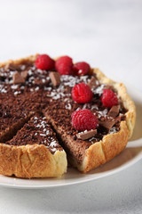 Chocolate cake with cottage cheese and raspberries on a light background. Background image, copy space