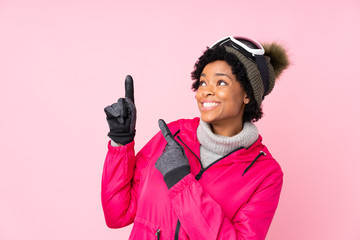 African american skier woman with snowboarding glasses over isolated pink background pointing with the index finger a great idea