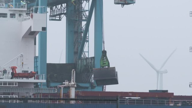 Downward pan of machinery loading cargo into containers on a ship