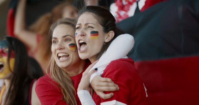 German spectators in stadium cheering together. People from Germany in fan zone cheering for their national team.