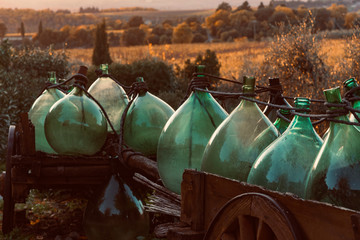 glass demijohn in the wooden cart in chianti in autumn