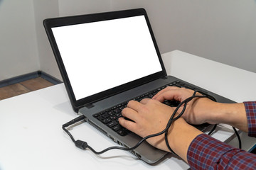 Modern problems concept. Man typing on laptop with hands tangled in the cable