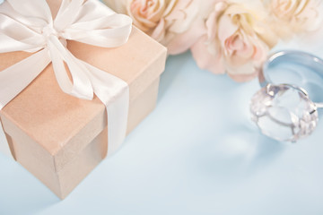 Gift box with flowers beige roses and big diamond ring on the background. Copy space