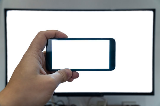 Seeing only through a screen concept. Man holding phone in front of a tv