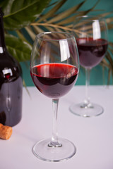 Two glasses with red grape wine with bottle on the background. Romantic dinner concept.