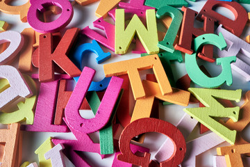 Multi-colored letters of the English alphabet are scattered in a mess on a white background