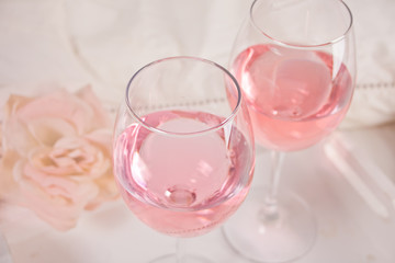 Two glasses with pink grape wine with flowers. Romantic dinner concept.