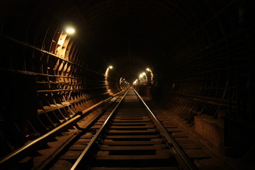A railway in a tunnel going off into the distance in the dark