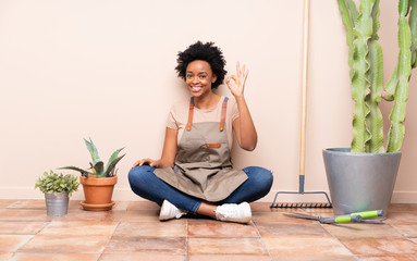 Gardener woman sitting on the floor showing ok sign with fingers