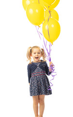 Fototapeta na wymiar smiling 3 year old Caucasian girl with pigtails holding yellow balloons.