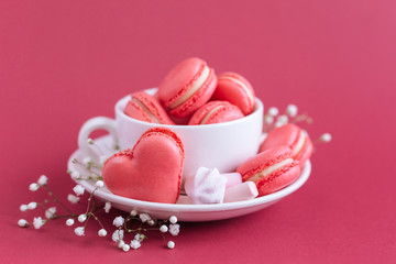 Valentine's day background with pink french heart-shaped macarons and marshmallows.