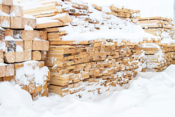 Building materials in the winter, wooden planks and bars for sale on the construction of a house
