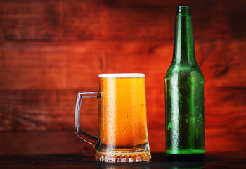 full mug of beer with foam and empty bottle
