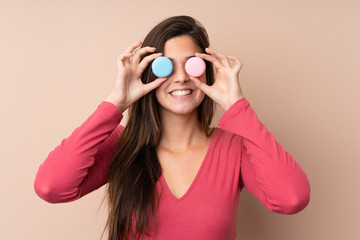 Teenager girl over isolated background wearing colorful French macarons as glasses