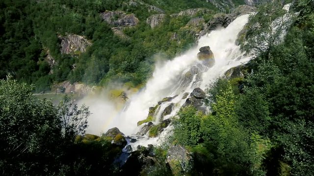 Rainbow and waterfall with melting water of the Briksdal glacier in Norway, arm of Jostedalsbreen glacier in Oldedalen valley in Norway, Scandinavia.