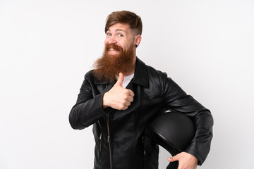 Redhead man with long beard holding a motorcycle helmet over isolated white background giving a thumbs up gesture