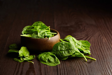 Spinach fresh green leaves in a wooden bowl