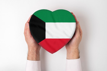 Flag of Kuwait on a heart shaped box in a male hands. White background