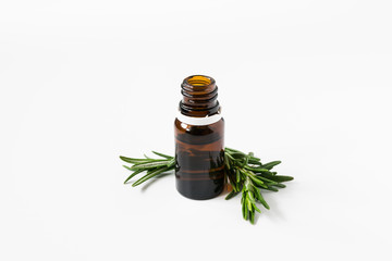 isolated glass bottle with aromatic oil and a sprig of rosemary on a white background