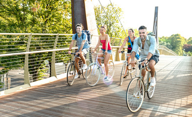 Happy millenial friends having fun riding bike at city park - Friendship concept with young...