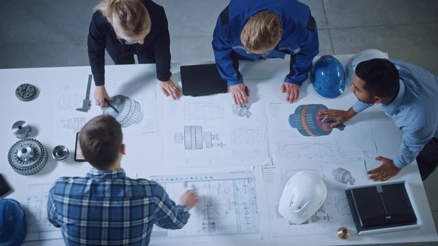 Team of Industrial Engineers Lean on Office Table, Analyze Machinery Blueprints, Architectural Problem Solving, Consult Project on Tablet Computer, Inspect Metal Component. Flat Lay Top Down View