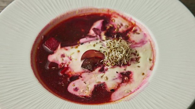 top view closeup traditional red borscht decorated with sour cream and wheat sprouts
