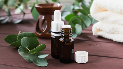 bottles with essential oil and eucalyptus leaves on a wooden table against the background of aromalamps and chickens