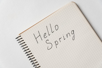 Notepad with the words Hello spring. Copybook on white background, close up